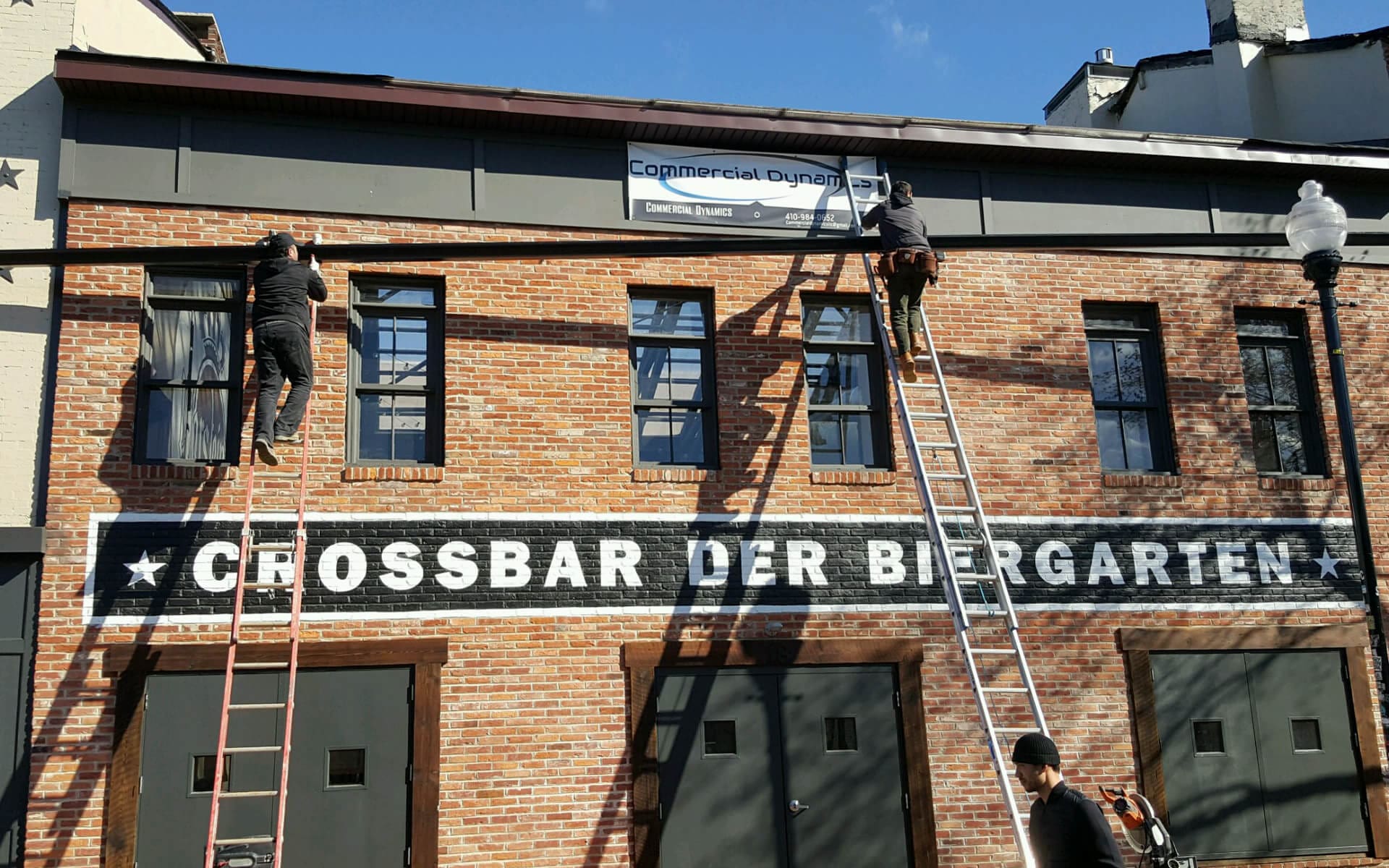 Next Day Gutters crew on ladders installing gutters on a brick commercial building