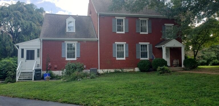 Red brick colonial with white trim, a side porch and new gutters