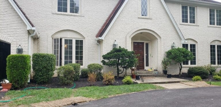 White painted-brick home with arched windows, a wood front door and white gutters