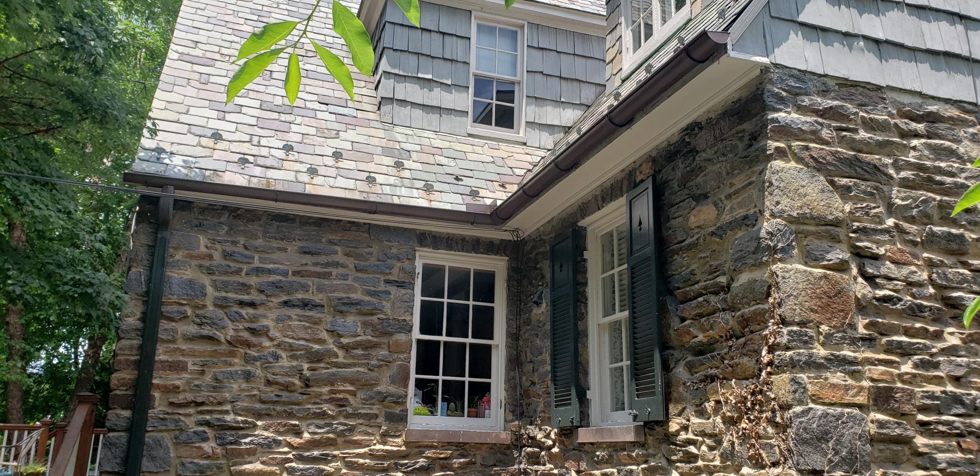 Stone colonial with royal brown half-round gutters and a matching round downspout
