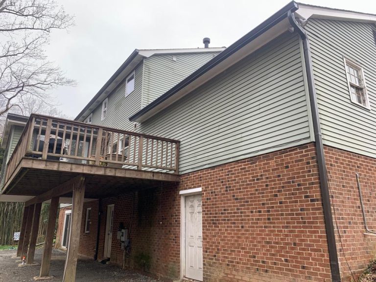 Brick and siding home with dark bronze gutters and downspouts